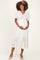 woman wearing a white maternity dress with short sleeves and tiered ruffles, cradling her baby bump