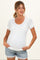 woman wearing a white short sleeve maternity top with button detail and ribbed texture, cradling her baby bump
