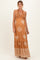woman wearing a rust-colored maternity maxi dress with white patterns and a halter neck, showing her baby bump