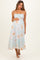 woman wearing a light blue floral maternity dress with spaghetti straps and a fitted waist, holding her baby bump