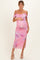 woman wearing a pink floral off-shoulder maternity dress with a slit and holding her baby bump