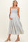 woman wearing a light blue floral maternity dress with smocked bodice and spaghetti straps, showing her baby bump