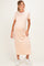 woman wearing a light peach short sleeve maternity dress with a relaxed fit and side pockets, holding her baby bump