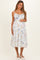 woman wearing a white floral maternity dress with adjustable straps and a visible baby bump