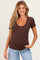 woman wearing a brown maternity top with a scalloped neckline and short sleeves, showing her baby bump