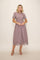 woman wearing a lavender mid-length dress with lace trim at the hem and short sleeves