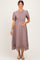 woman wearing a mauve maternity dress with short puff sleeves and lace trim, holding her baby bump