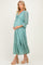 woman wearing a teal lace maternity dress with three-quarter sleeves and holding her baby bump