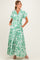 woman wearing a green floral patterned maternity maxi dress with short sleeves and a tied waist detail