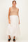 woman wearing a beige knitted crop top over a white maxi maternity dress, featuring a baby bump