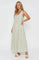 woman wearing a light green striped maxi dress with a v-neck and tiered skirt, standing sideways with hands in pockets