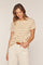 woman wearing a beige and cream striped t-shirt tucked into light-colored high-waisted pants