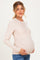 woman wearing a beige long sleeve maternity top and holding her baby bump