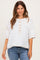 woman wearing a white maternity top with button details and short sleeves, styled with denim jeans