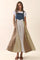 woman wearing a color-blocked maxi dress with a denim top and patterned skirt, standing with pockets
