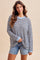woman wearing a striped oversized long sleeve top with light blue accents and denim shorts
