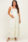 woman wearing a white floral maternity maxi dress with a square neckline and tying shoulder straps, gently cradling her baby bump