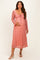 woman wearing a pink floral maternity dress with long sleeves and a tie front, holding her baby bump