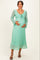 woman wearing a mint green lace maternity dress with long sleeves and a tie front, holding her baby bump