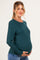 woman wearing a dark green long sleeve maternity top and showcasing her baby bump