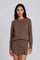 woman wearing a brown long sleeve top with a matching mini skirt and side slit