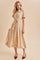 woman wearing a cream button-up midi dress with floral print and a tied waist, paired with brown heeled shoes