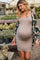 woman wearing a beige maternity dress with a floral kimono, showing her baby bump while walking in a greenhouse