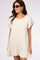 woman wearing a cream linen shift dress with frayed ruffle sleeves and hemline