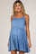 Pregnant woman wearing a light blue sleeveless tiered maternity dress against a neutral background