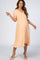 pregnant woman in peach swiss dot maternity midi dress with ruffle neckline and tan heels