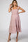 woman wearing a light pink maternity dress with tie straps and tiered skirt, showcasing her baby bump
