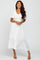 woman wearing a white v-neck midi dress with flutter sleeves and a tiered hem, standing in a relaxed pose