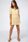 Woman wearing a cream tiered maternity mini dress with short puff sleeves and tassel neck tie