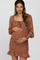 woman wearing a brown floral maternity dress with a square neckline and ruffle hem, holding her baby bump