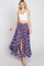 woman wearing white crop top and purple floral maxi skirt with front slit and tassel drawstring
