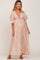 woman wearing a blush pink maternity maxi dress with a plunging neckline and buttons, showcasing her baby bump