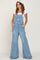 woman wearing light wash distressed denim overalls with wide legs and a white t-shirt