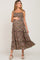 Pregnant woman wearing a floral smocked maternity midi dress with tie straps and white wedge sandals