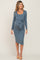 woman wearing a slate blue long sleeve maternity dress with a tie detail and visible baby bump