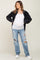 pregnant woman wearing white maternity tank top, black corduroy jacket, and distressed blue jeans