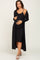 woman wearing a black ribbed maternity dress with a matching long cardigan and holding her baby bump