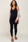 woman wearing a black maternity bodysuit paired with a light cardigan, showing her baby bump