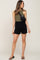 woman wearing olive green halter top black smocked shorts and a black crossbody belt bag