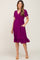woman wearing a purple short sleeve wrap maternity dress with ruffle hem and pockets, showcasing her baby bump