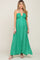 woman wearing a green printed halter neck maternity maxi dress with white sandals