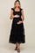woman wearing a black maternity dress with ruffle straps and tiered tulle skirt, holding her baby bump