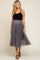 woman wearing a black maternity tank top and a gray tulle midi skirt, showing off her baby bump