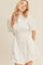 woman wearing a white puff sleeve shirt dress with a button-up front and a gathered hem