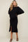 woman wearing a black maternity sweater and matching skirt with a side slit, showing her baby bump