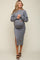 woman wearing a gray maternity sweater and matching skirt with side slit, displaying her baby bump